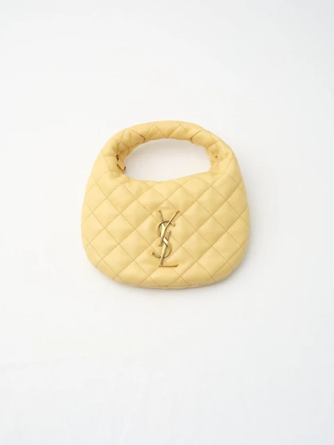 Light yellow quilted leather top-handle handbag with gold-tone YSL logo on a clean white background in a studio product shot.