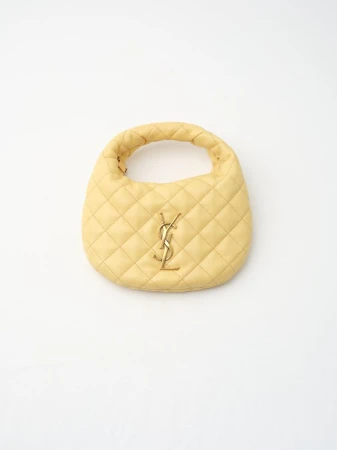 Light yellow quilted leather top-handle handbag with gold-tone YSL logo on a clean white background in a studio product shot.