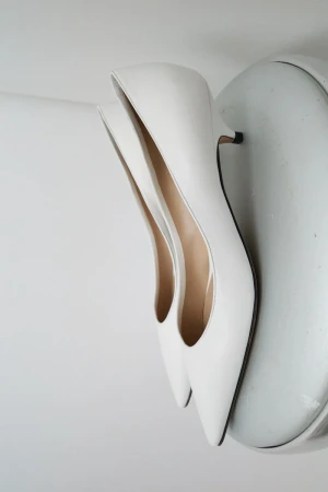 Elegant white heeled shoes on a white surface, perfect for fashion and beauty-related content. Minimalist aesthetic.