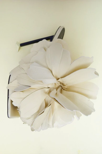 Elegant handbag with oversized fabric flower detail in a studio setting on a light backdrop, fashionable and eye-catching.