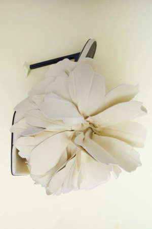 Elegant handbag with oversized fabric flower detail in a studio setting on a light backdrop, fashionable and eye-catching.