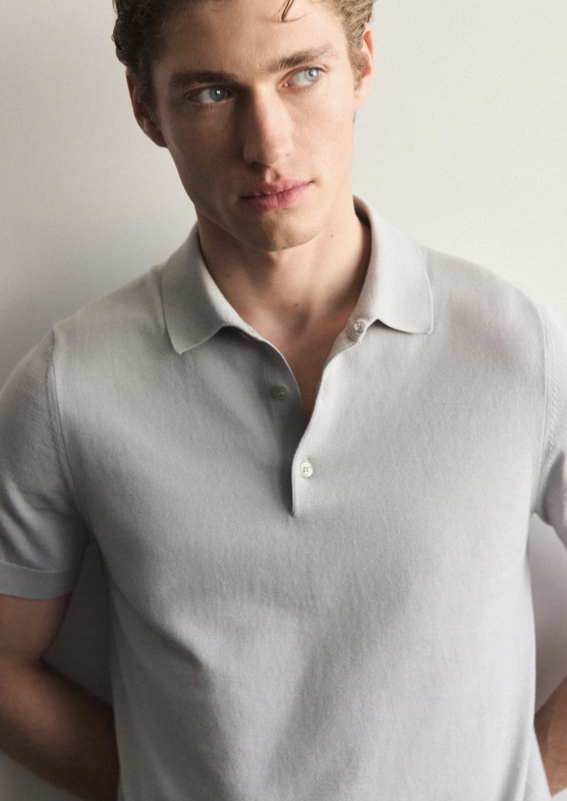 Headshot of adult male with blond hair and blue eyes wearing a grey polo shirt in front of a neutral-colored background.