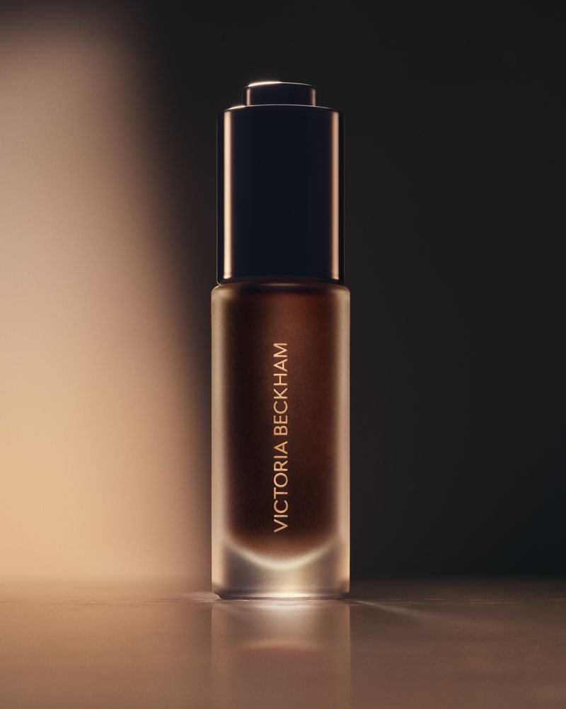 Victoria Beckham Beauty foundation bottle in a beauty shot featuring a sleek bottle design with a dropper, against a soft gradient background.