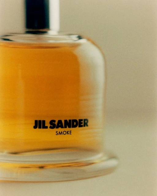 Close-up of Jil Sander Smoke perfume bottle, showcasing its sleek design, transparent glass, and amber-colored fragrance liquid.
