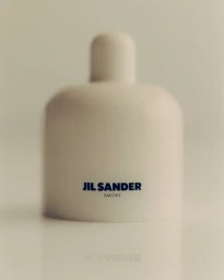 Minimalist white Jil Sander fragrance bottle centered on a pale seamless background