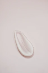 Close-up of a white cosmetic cream swatch on a matching pale pink background.