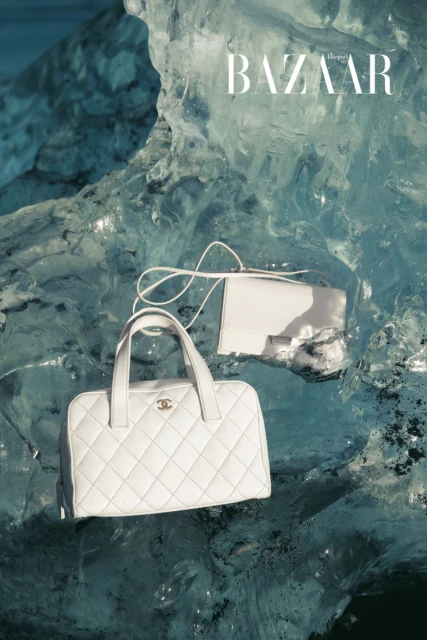 Fashion editorial shot of white quilted Chanel handbags against a backdrop of textured blue ice. Bazaar logo visible in the upper right.
