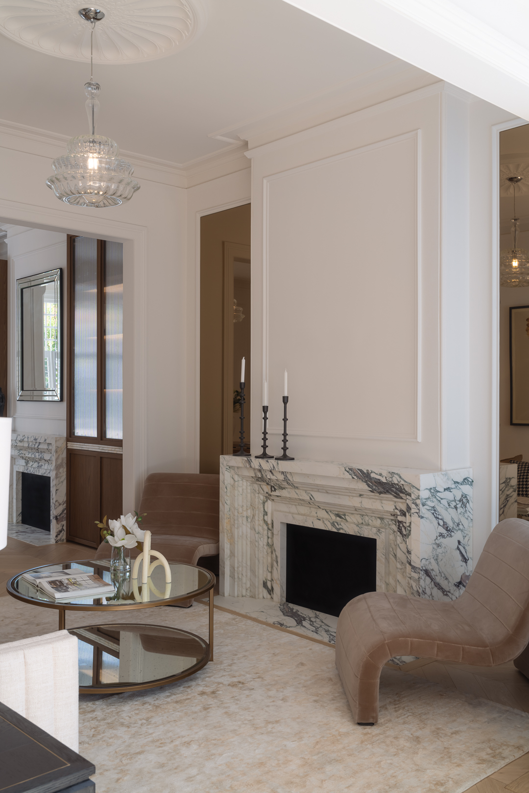 Living room interior showcases fireplace with marble surround, modern furniture arrangement, and decorative lighting fixture.