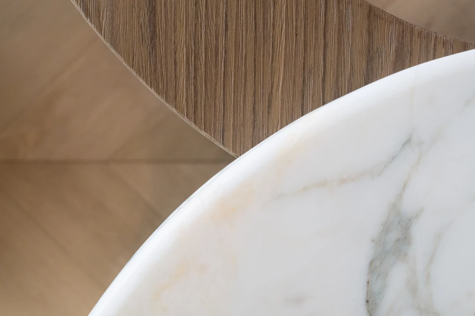 Close-up of a table featuring a white marble top, complemented by wooden inlays of various textures, showcasing modern design.