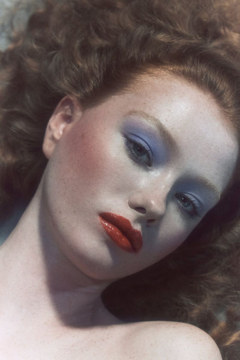 Close-up beauty portrait of a red-haired model with blue eyeshadow and red lips from the DOLLS project.
