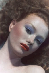 Close-up beauty portrait of a red-haired model with blue eyeshadow and red lips from the DOLLS project.