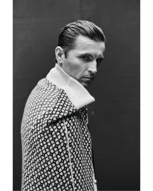 Portrait of actor Raphaël Quenard in a patterned high-neck sweater looking over his shoulder for Crash Magazine.