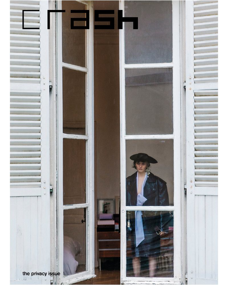 Fashion magazine cover: a woman in a jacket and hat stands framed by an open window with white shutters, promoting the Privacy Issue.