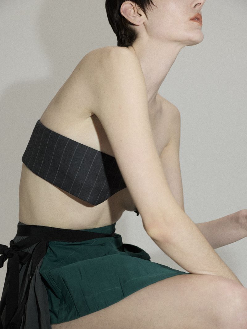 Woman posing in striped top and green skirt in a studio setting. Fashion-forward editorial style in studio light.