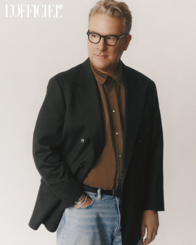 Mature man wearing glasses, a button-down shirt, blazer and light jeans in a portrait shot with magazine logo visible in the frame.