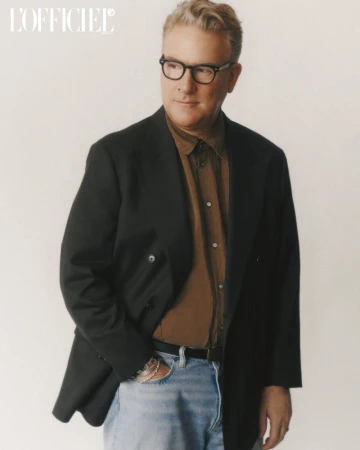 Mature man wearing glasses, a button-down shirt, blazer and light jeans in a portrait shot with magazine logo visible in the frame.