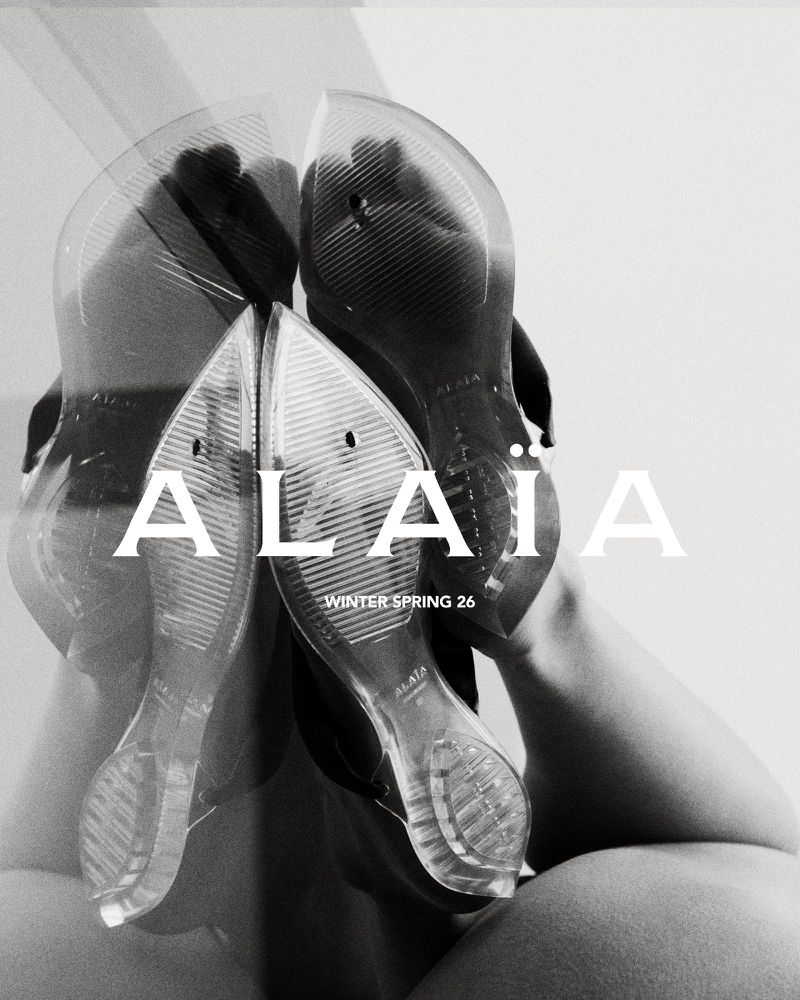 Artistic close-up of transparent women's shoes with 'Alaia Winter Spring 26' text overlay against a blurred, monochrome background.