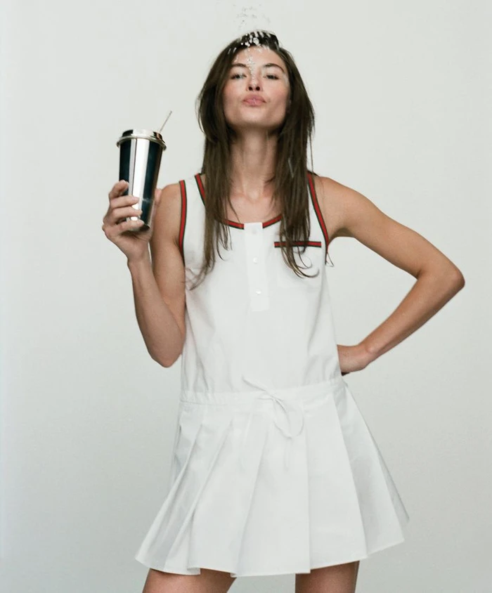 Model Grace Elizabeth holding a metallic tumbler wearing a white tennis dress for WSJ project Hello, Summer! photographed by Stevie Dance