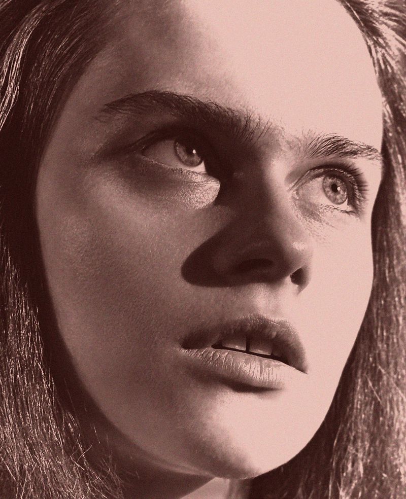 Close-up portrait of a young adult female with light skin and long hair, looking upwards and to the side in a monochrome image.