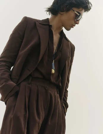 Model in brown suit and dark sunglasses against a seamless white background for Vogue Scandinavia