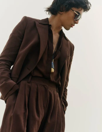 Model wearing a brown suit and sunglasses against a plain white background for Vogue Scandinavia