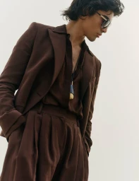 Model wearing a brown suit and sunglasses against a plain white background for Vogue Scandinavia