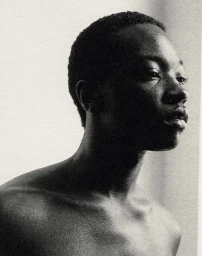 Monochrome portrait of a black man in profile looking away against a textured light background.