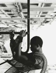 Black and white portrait of a model holding onto a metal railing against a blurred urban background