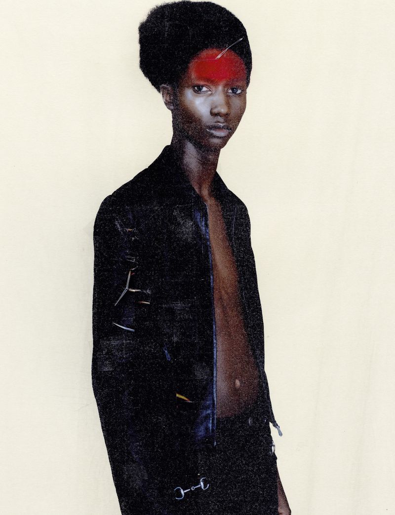Close-up studio portrait of an African American fashion model with dark hair and a black jacket against a light background.