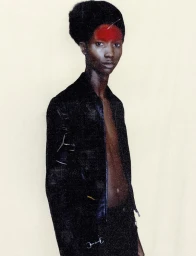 Black male model with red forehead makeup wearing a dark jacket against a light background