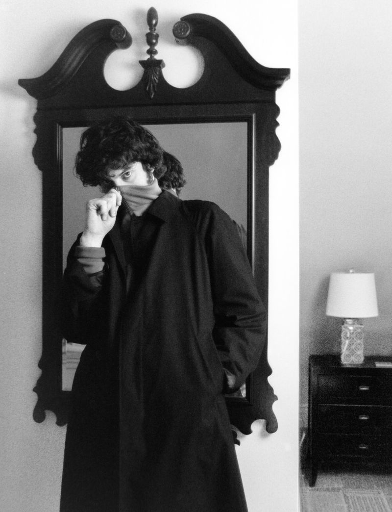 Monochrome portrait of actor Dominic Sessa in a dark coat standing before an ornate mirror for HERO Magazine.