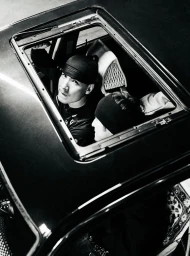High-angle black and white shot of two people looking up through an open car sunroof