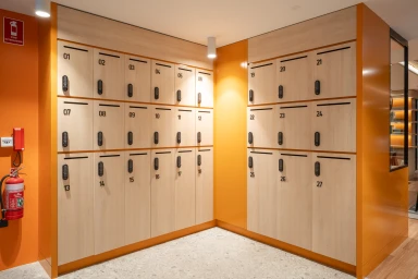 Modern wooden lockers with digital locks installed in a vibrant orange corner alcove by Intermain for 3 Hosking Place