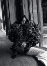 Model Kinari Tamukai in voluminous patterned top and dark gloves seated on wooden veranda for 5ELEVEN Magazine