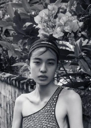 Monochrome portrait of Kinari Tamukai wearing a patterned top and headband against lush foliage for 5ELEVEN Magazine