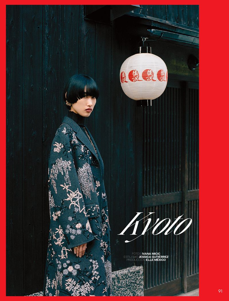 A fashionable Asian woman in a floral coat poses outdoors next to a lantern in Kyoto, Japan, fashion editorial for Elle Mexico.