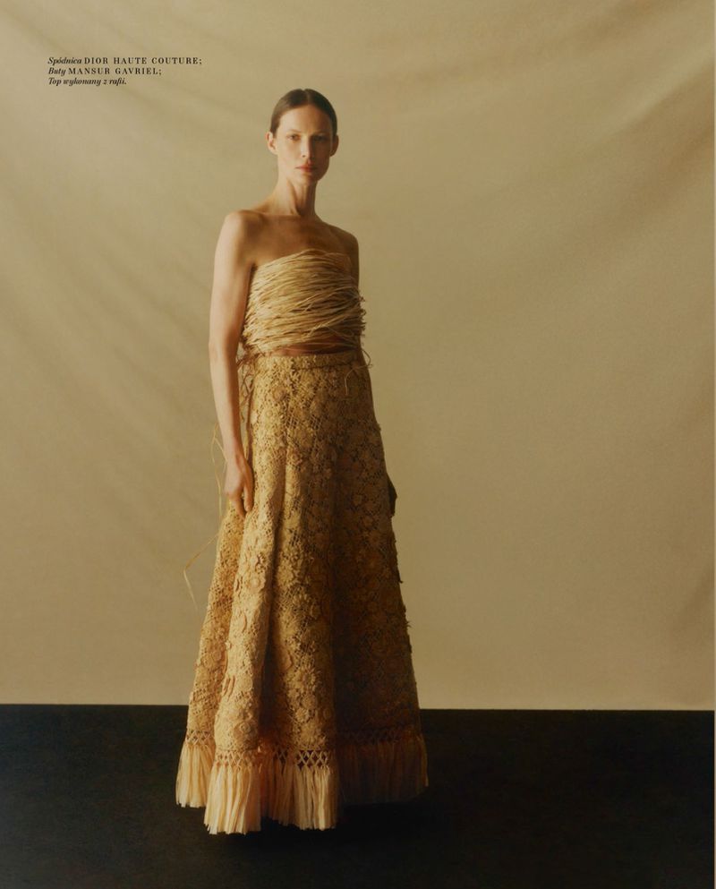 Model standing in a structured strapless textured top and long skirt against a neutral background for Vogue Polska