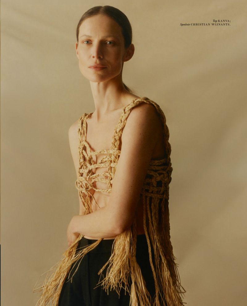 Model wearing a woven straw top and dark trousers against a neutral background for a Vogue Polska fashion editorial.