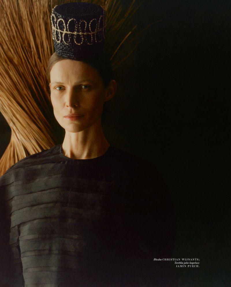 Model wearing a dark structured hat and black top against a dark background for Vogue Polska PLECIONKA editorial.