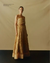 Model standing in a structured strapless textured top and long skirt against a neutral background for Vogue Polska
