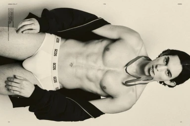 Close-up portrait of a male model wearing white branded briefs and a black jacket against a seamless background
