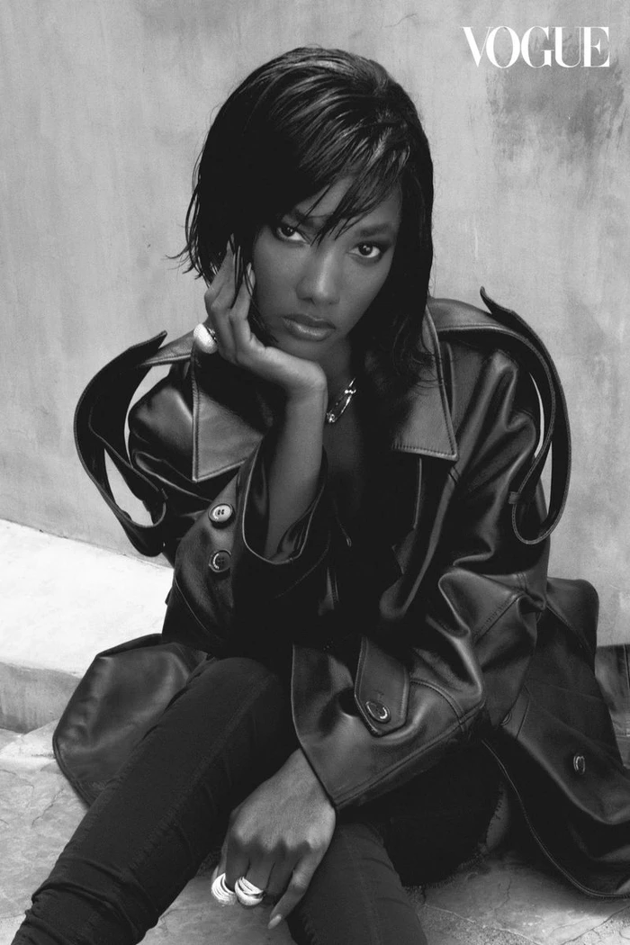 Black-and-white fashion portrait of Mariama Diallo wearing a dark leather jacket and rings against a textured wall