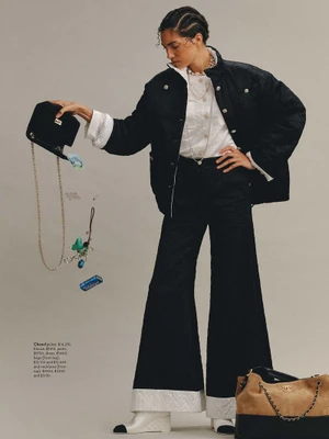 Model in black jacket and trousers holding an overturned handbag spilling items, for Marie Claire Australia.