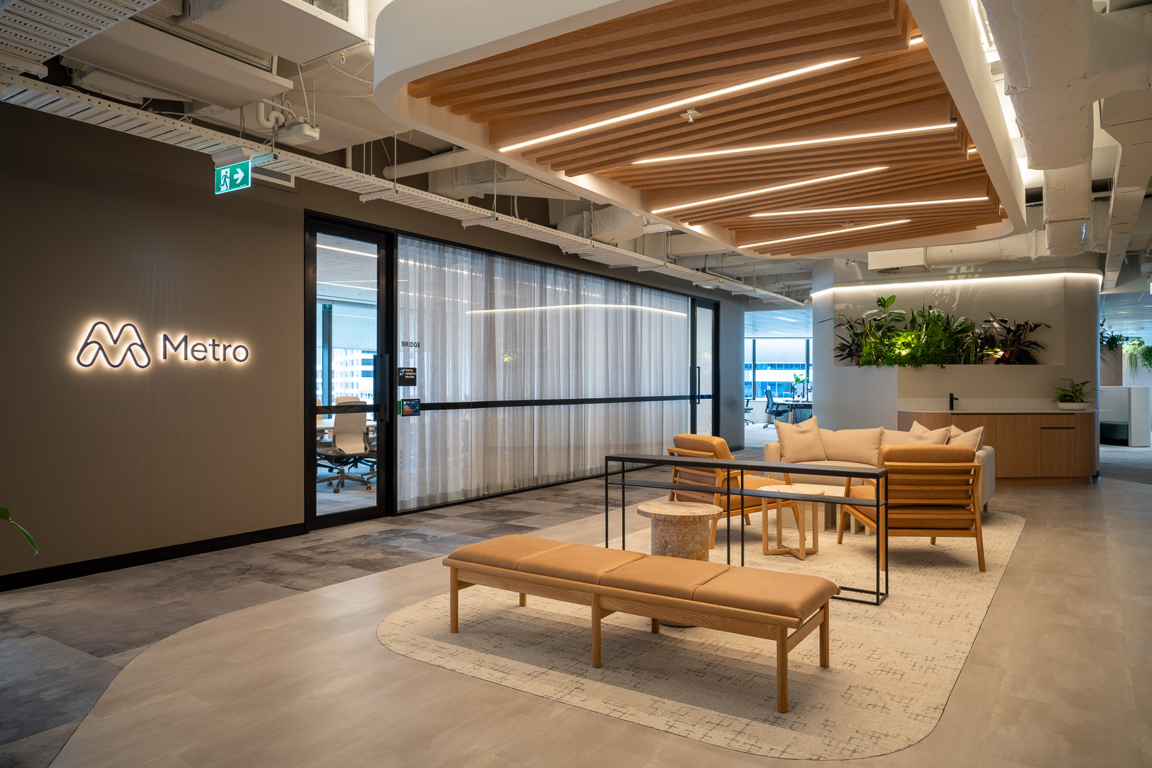 Interior view of a modern office lobby with lounge seating, wood accents, concrete floors, and the Metro logo on a wall.