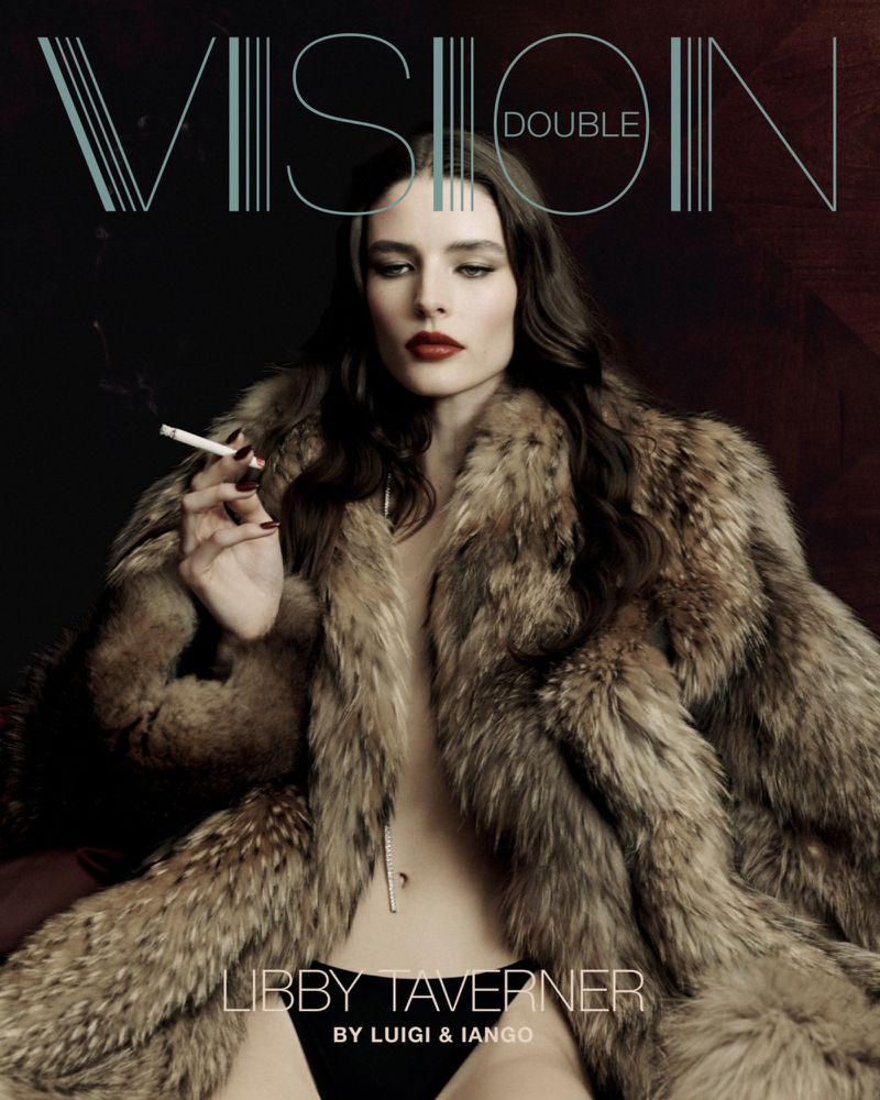 A woman with long, dark hair poses with a cigarette while wearing a fur coat in a studio fashion shot.