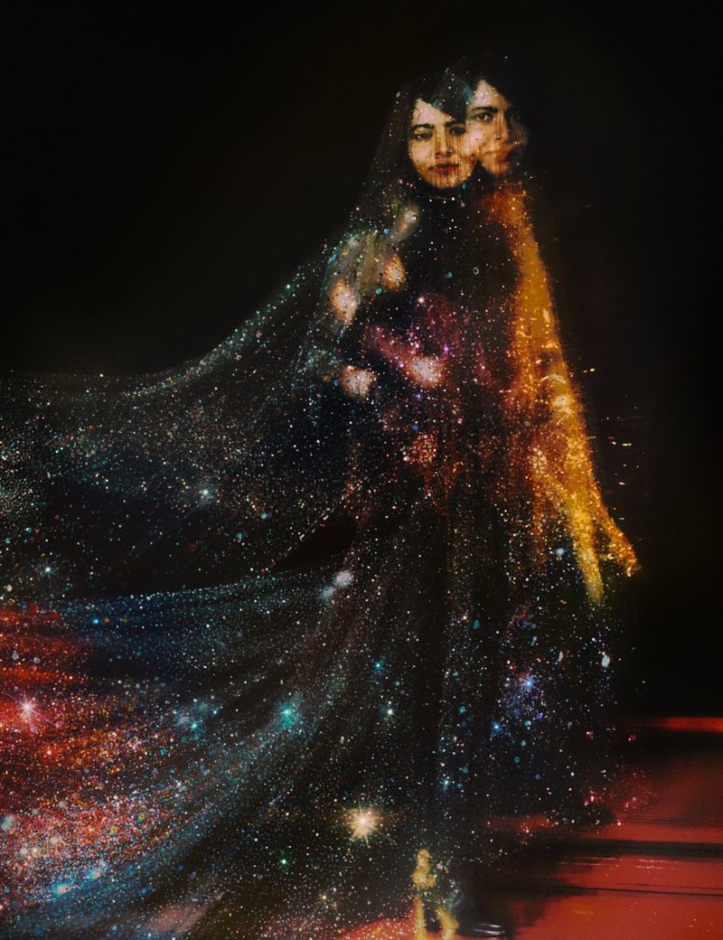 Surreal digital artwork of two women enveloped in a sparkling, star-like material, set against a dark background with a reflective surface.