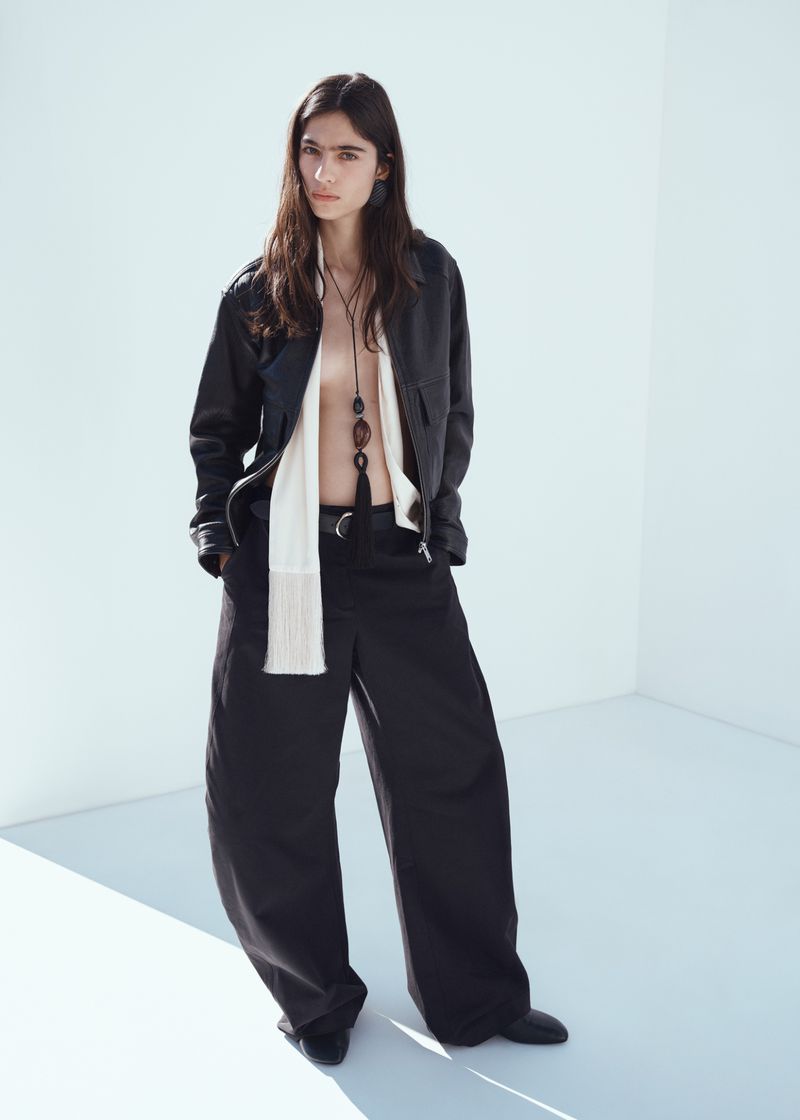 Model Loli Bahia wearing a black leather jacket and trousers against a white seamless background
