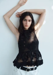 Model Loli Bahia posing in a black lace halter top and white jeans against a plain white background for H&M.