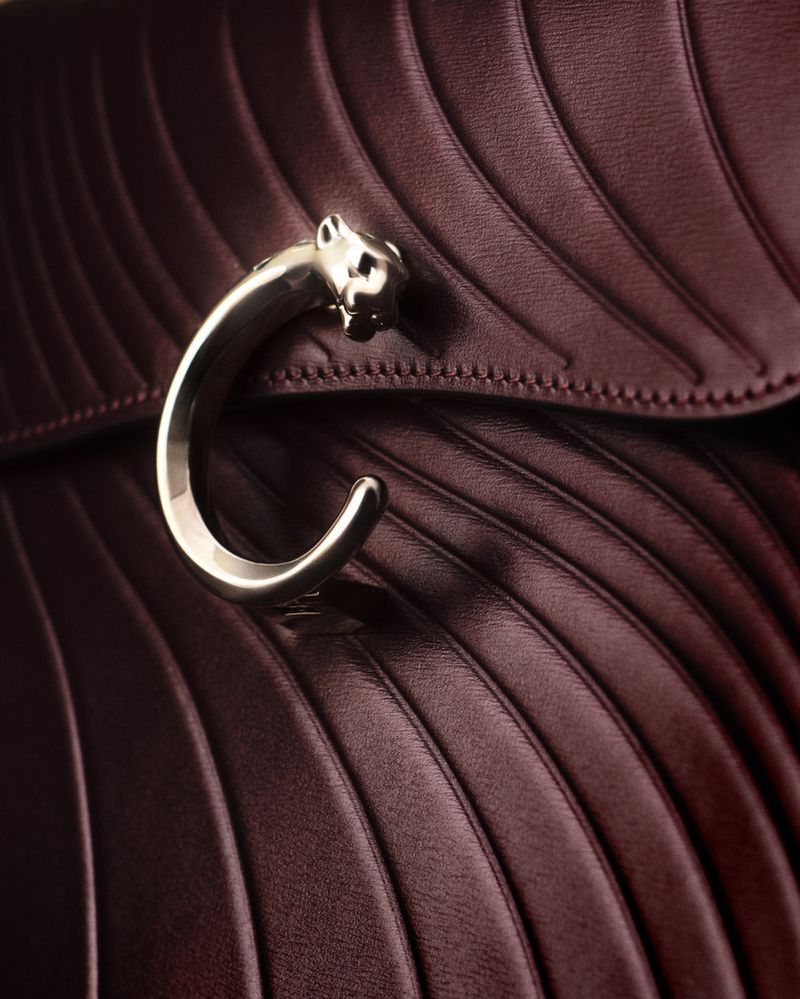 Close up of a deep burgundy leather bag with quilted curved lines and a silver panther clasp handle for Vogue