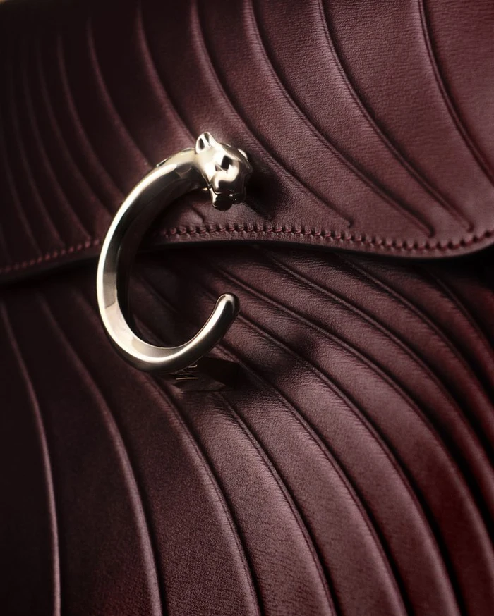 Close up of a deep burgundy leather bag with quilted curved lines and a silver panther clasp handle for Vogue